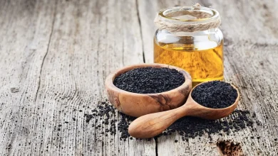 تصویر بطری حاوی روغن سیاهدانه در کنار کاسه و قاشق حاوی دانه های سیاهدانه