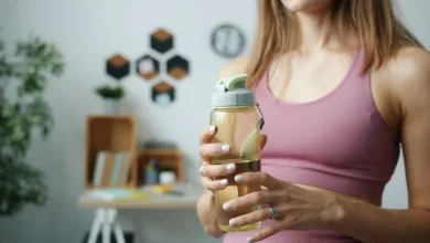 آیا کراتین باعث یبوست می شود؟ تصیور زنی با لباس ورزشی و بطری حاوی محلول کراتین